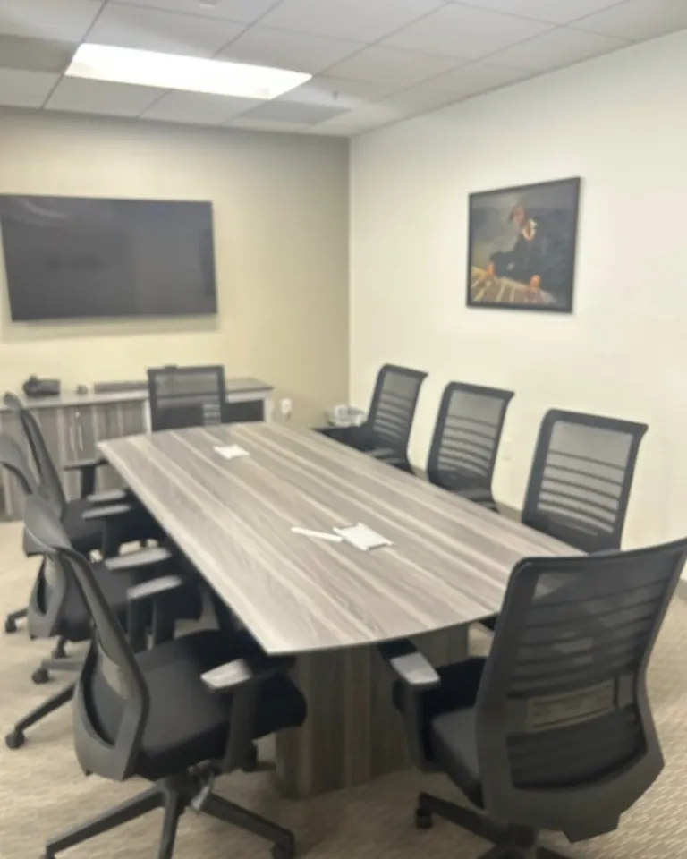 The large conference room at ABC Virtual Offices in Beverly Hills, with a long table, mesh office chairs and a wall-mounted TV